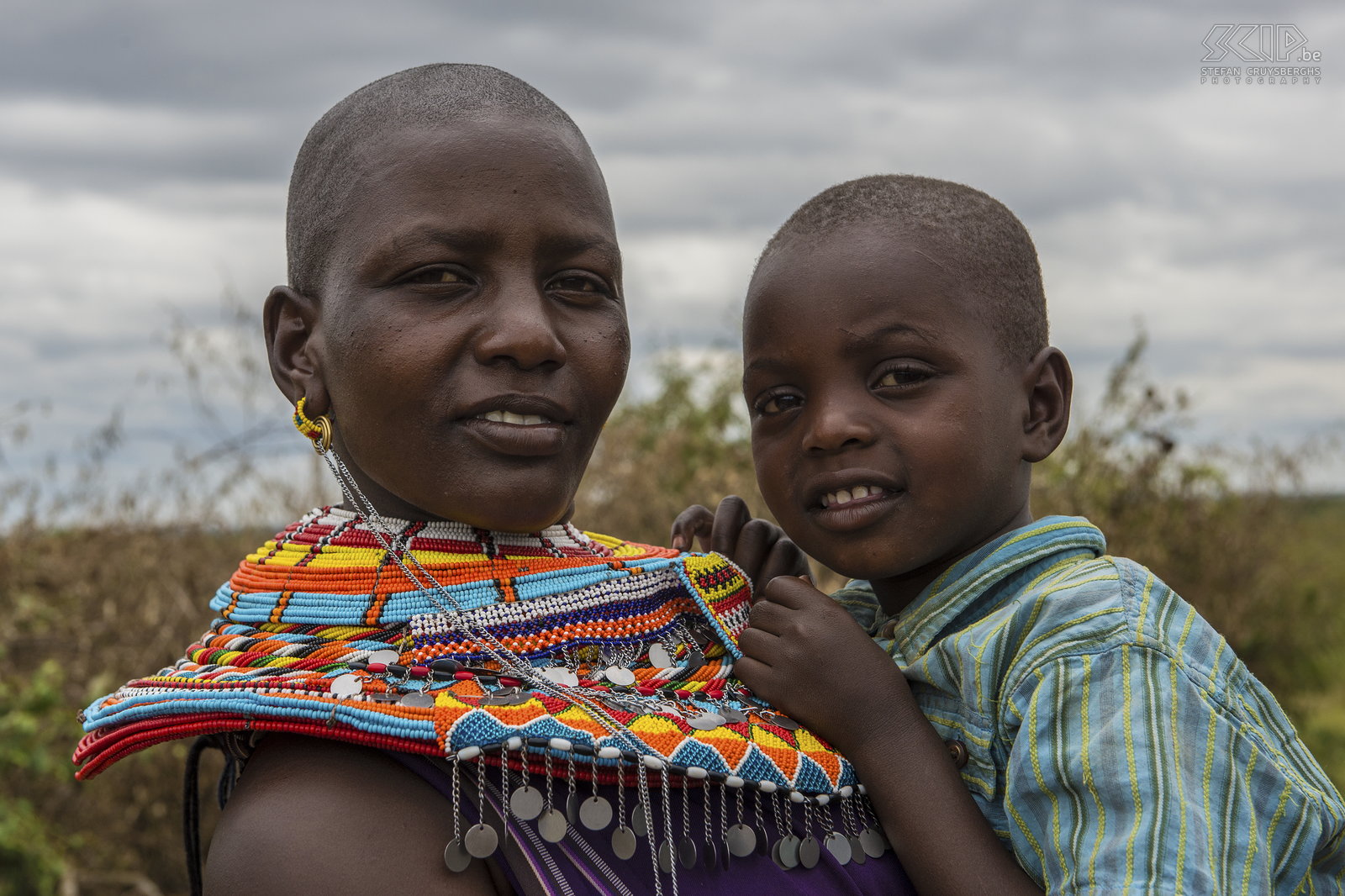 Kisima - Samburu lmuget - Vrouw met kind Samburu meisjes krijgen allerlei kralen van hun vaders als ze jong zijn. Zodra ze ouder zijn, krijgen ze veel cadeaus van hun moran geliefden en zo dragen ze op den duur heel veel lagen van kralen halskettingen. Samburu vrouwen dragen allen kleurrijke rokken en doeken. Stefan Cruysberghs